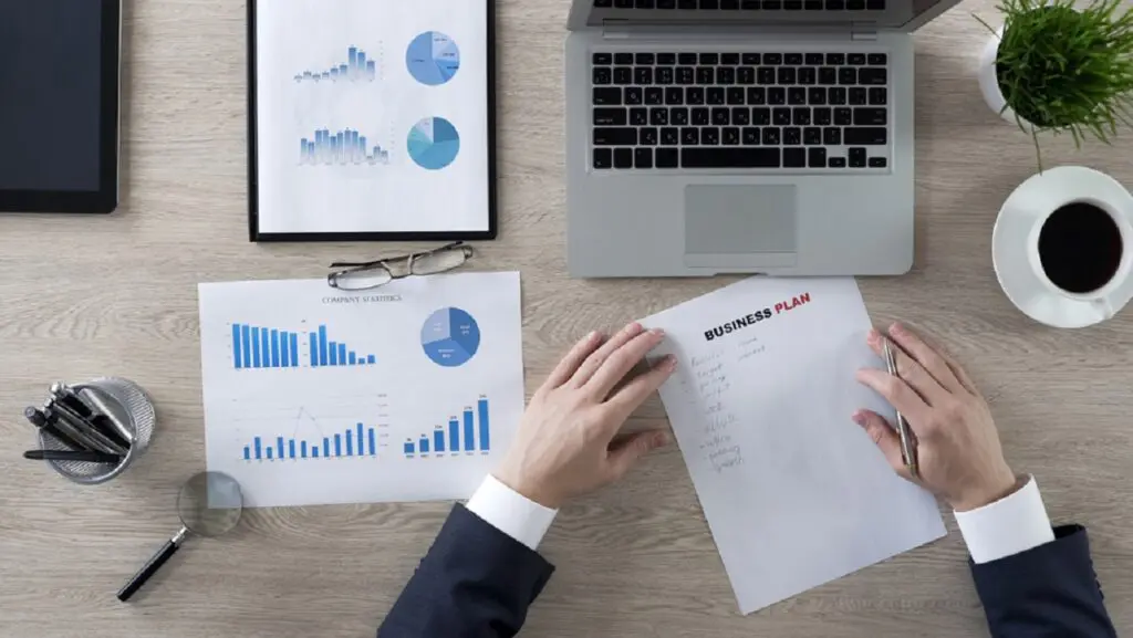 A person sitting at a table with papers and a laptop
